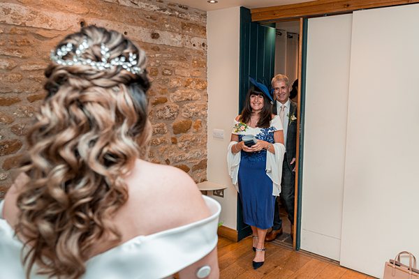 Bride facing guests arriving at wedding ceremony.