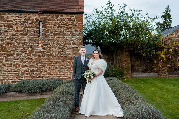 Bride and groom smiling outside stone building.