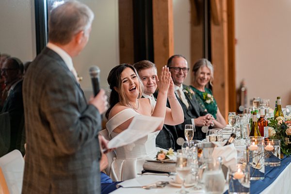 Bride laughing during wedding reception speeches.