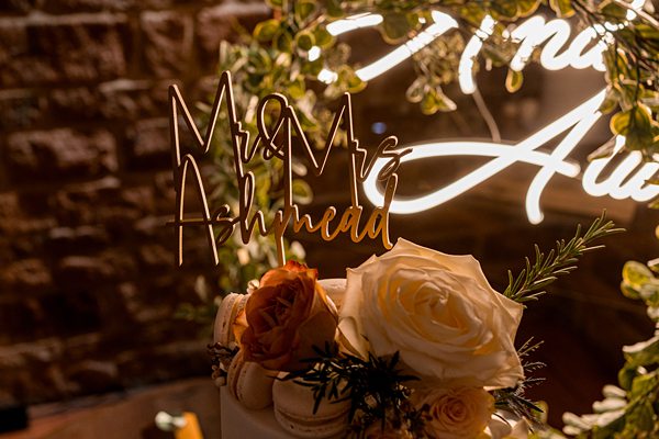 Wedding cake with "Mr & Mrs" topper and white roses.