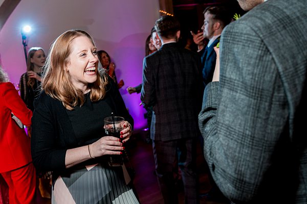 Woman laughing at party with drink in hand.