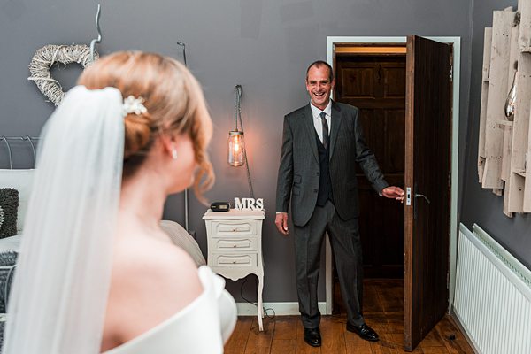 Bride smiling at groom entering room.