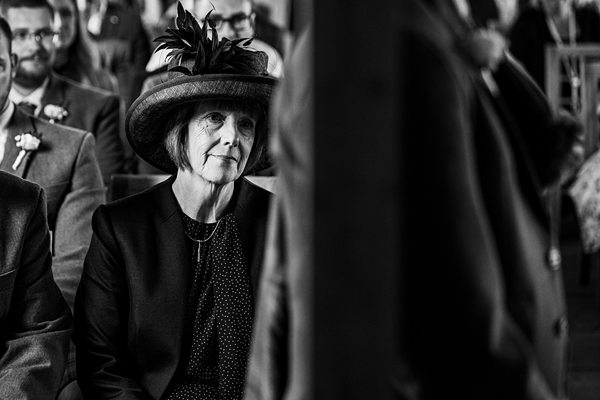 Elderly lady wearing hat at formal event.