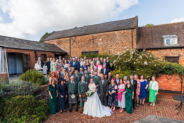 Wedding guests posing outside brick venue.