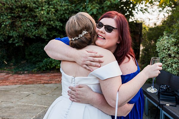 Two women embracing at outdoor celebration.