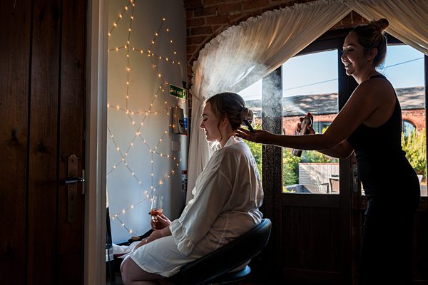 Bride getting hairstyle by stylist near twinkling lights at Dodmoor House