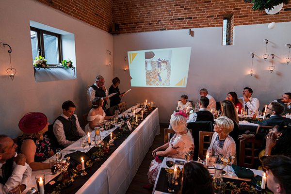 Wedding reception with guests watching slideshow presentation.