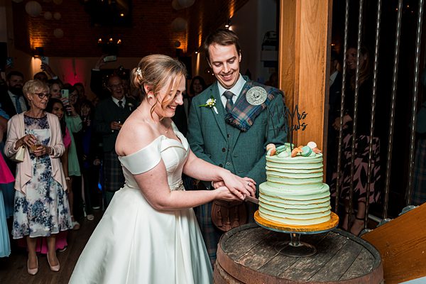 Bride and groom cutting wedding cake together.