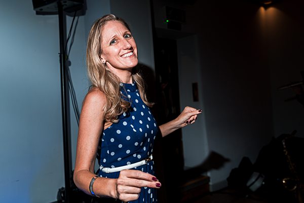 Woman smiling in blue polka dot dress at event.