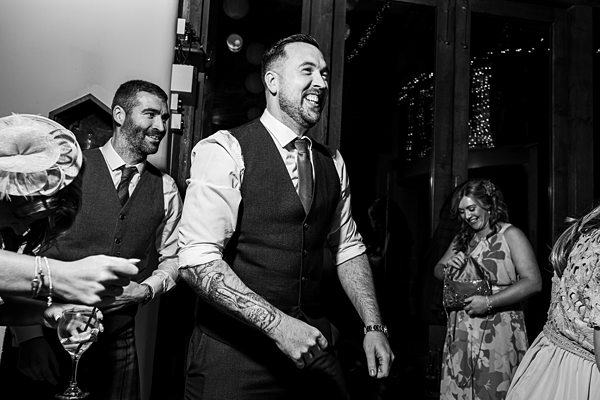 Men in waistcoats laughing at festive event.