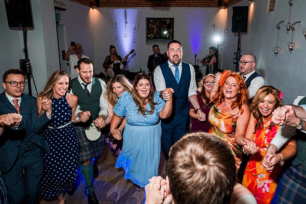 Wedding guests dancing at lively reception.