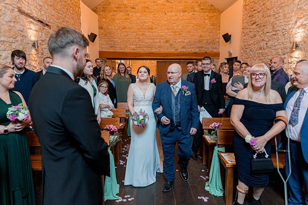 Bride walking down aisle at wedding ceremony.
