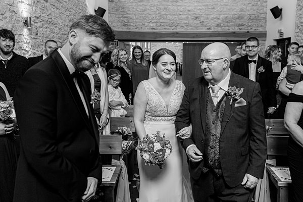 Bride walking down aisle with father, wedding ceremony, guests.