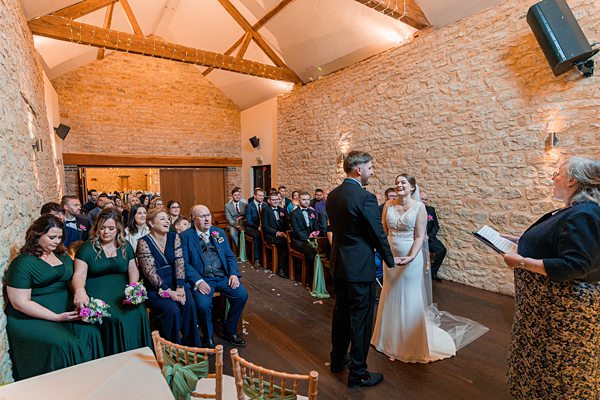 Couple at indoor wedding ceremony with guests.