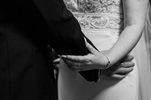 Couple holding hands at wedding ceremony.