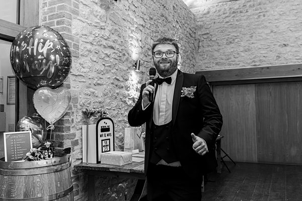 Man giving speech at event with balloon and decorations.