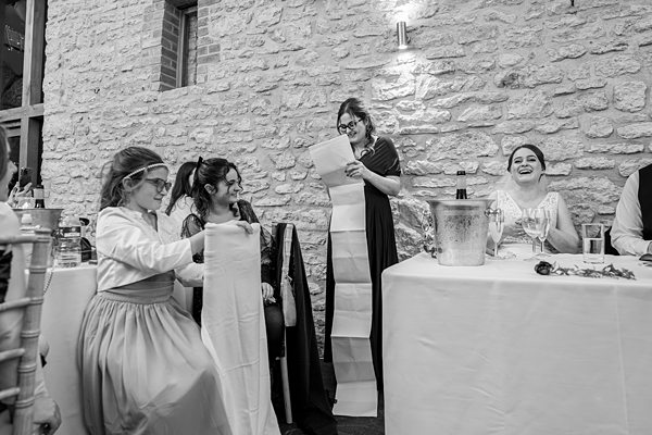 Woman reading at wedding, guests laughing.