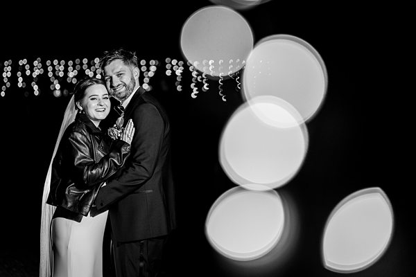Couple embracing at night, white balloons and lights.