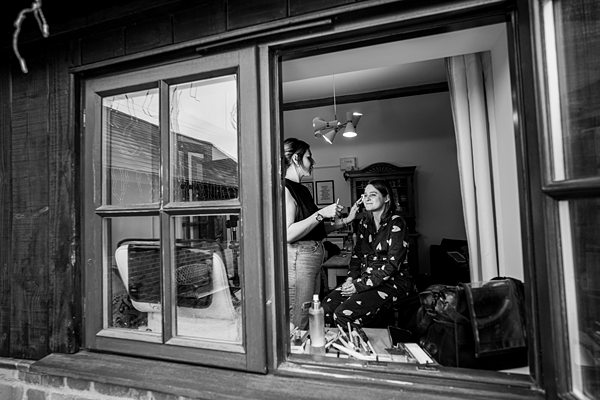 Makeup artist applying cosmetics to a woman indoors.
