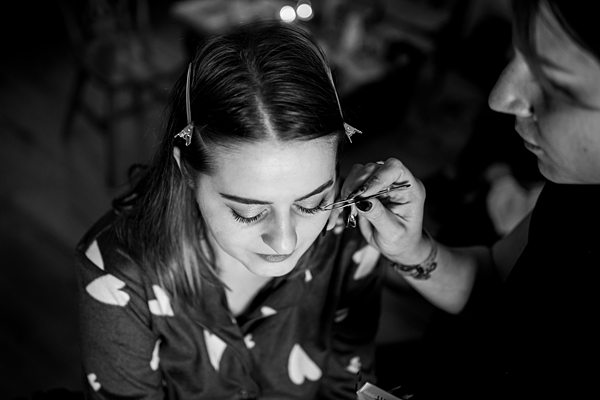 Makeup artist applying mascara to woman.