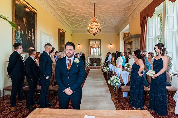 Groom waiting in elegant room with wedding guests.