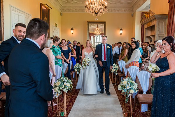 Bride walking down aisle at elegant wedding ceremony.