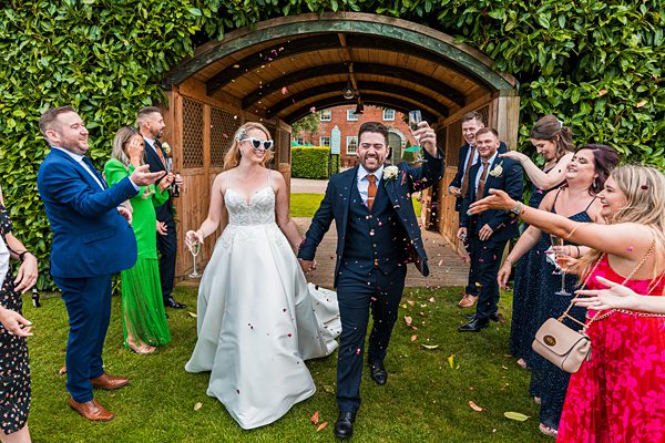 Bride and groom enjoying confetti toss at wedding.