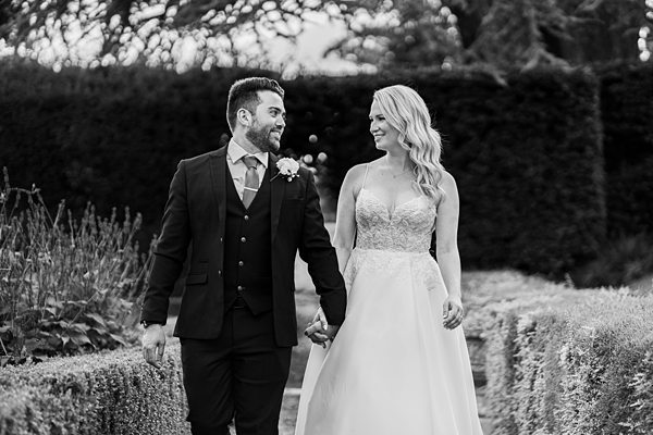 Couple walking hand in hand in wedding attire.