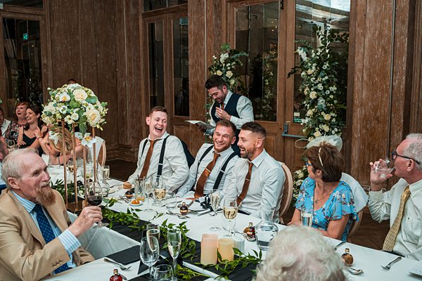 Joyful wedding reception with laughing guests at dinner table.