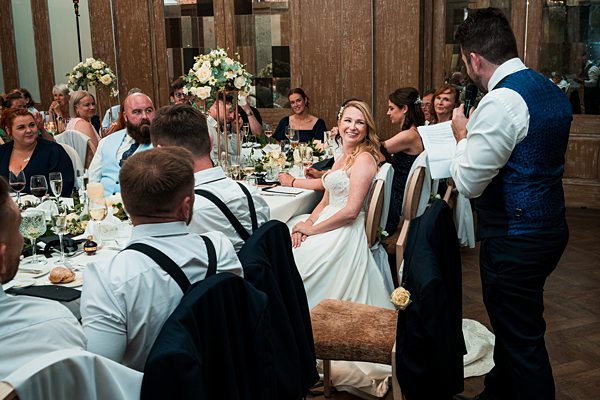 Wedding reception speech with smiling guests.