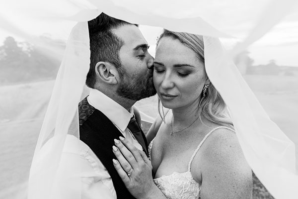 Bride and groom sharing intimate moment under veil.