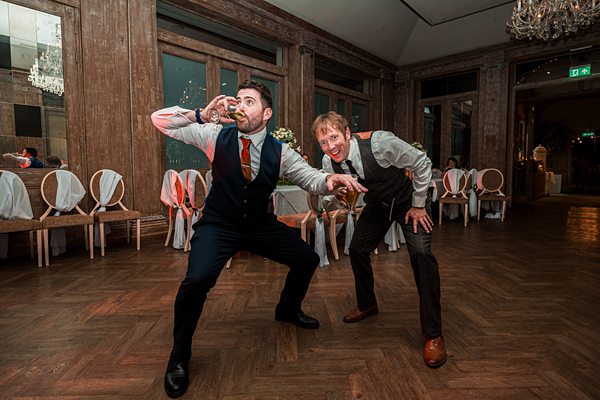 Men posing humorously at wedding reception.