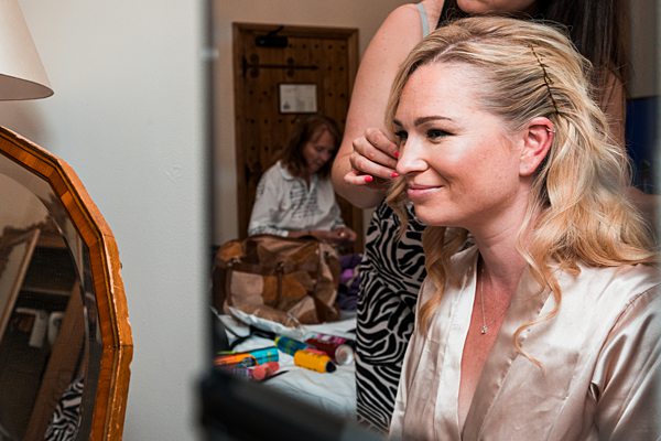 Woman getting makeup done in room with mirror reflection.