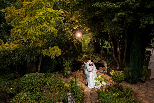 Couple embracing in serene garden at dusk.