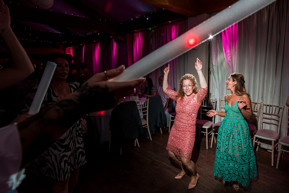 Guests dancing with glow sticks at evening party.