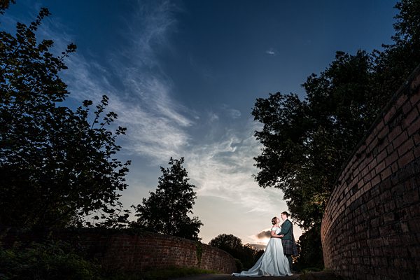 Couple embracing at sunset, dramatic sky.