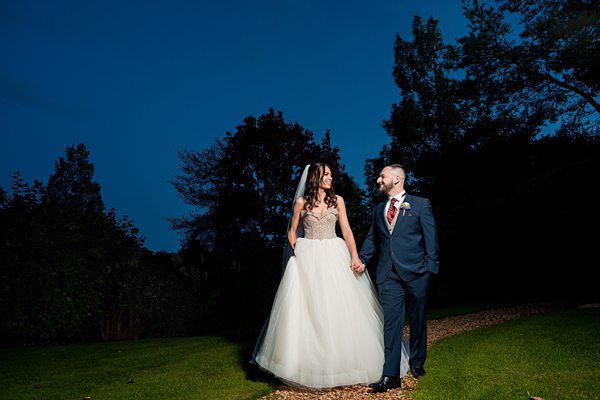 Evening garden wedding, couple holding hands, smiling.