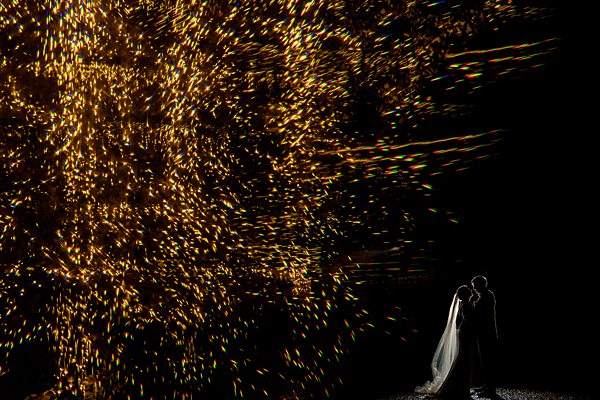 Couple kissing under sparklers at night.