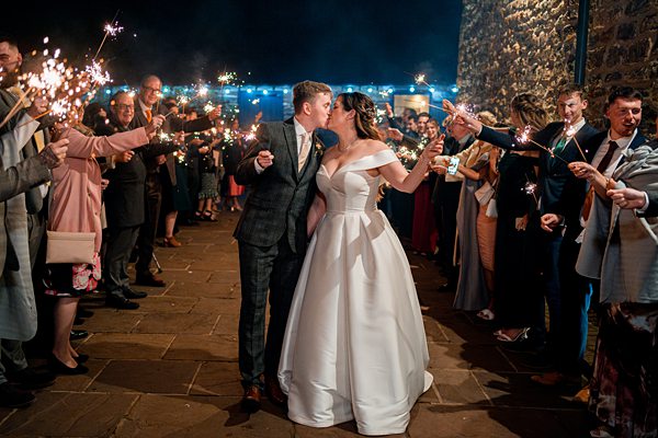 Bride and groom with sparklers at wedding celebration.