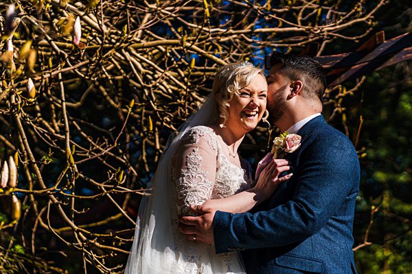Joyful wedding couple embracing outdoors in sunlight.