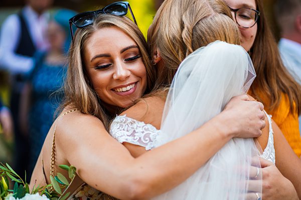Wedding embrace, joyful woman hugging bride outdoors.