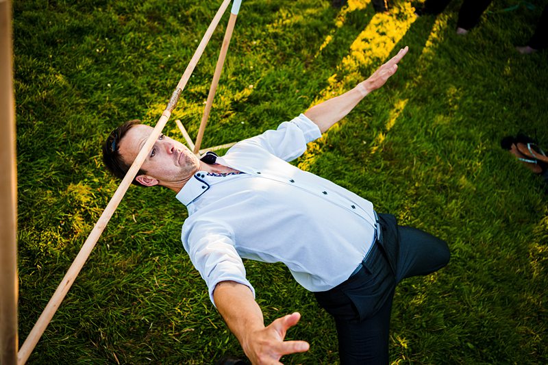 Man balancing under limbo stick at outdoor event.