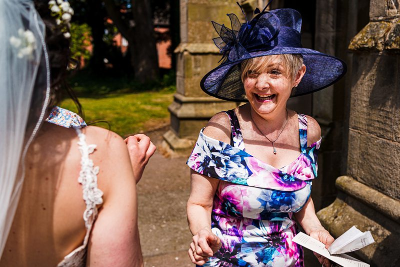 Woman in floral dress and hat at wedding.