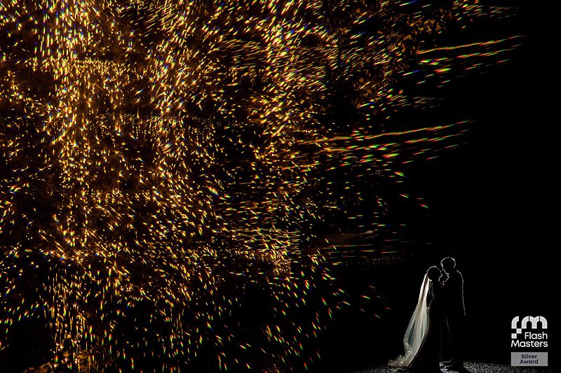 Couple silhouetted against sparkling fireworks display.