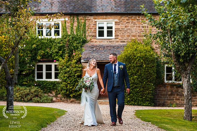 Couple walking hand in hand at countryside wedding.