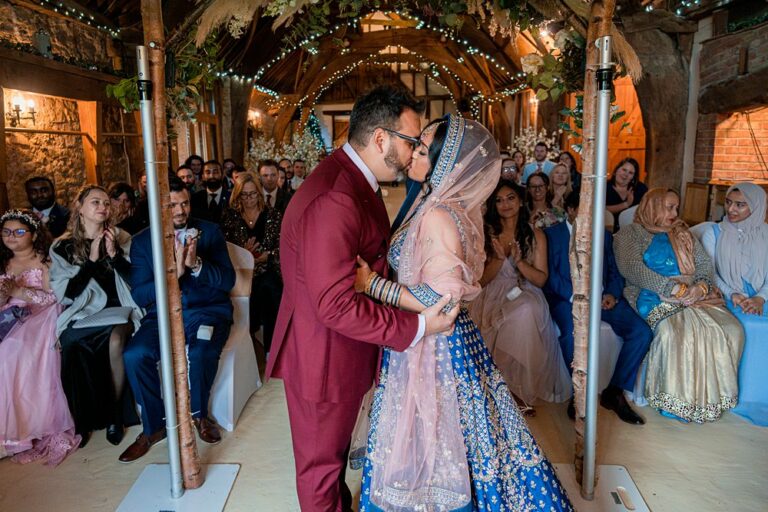 Bride and groom kissing at multicultural wedding ceremony.