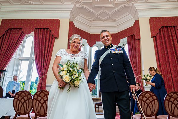 Bride and groom smiling in wedding ceremony hall.