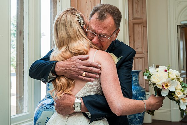 Bride and father embracing on wedding day.