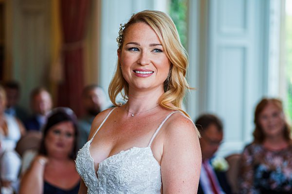 Bride smiling at indoor wedding ceremony.