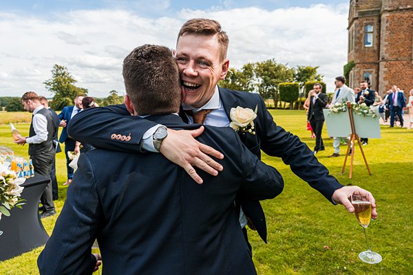 Men embracing at outdoor wedding celebration